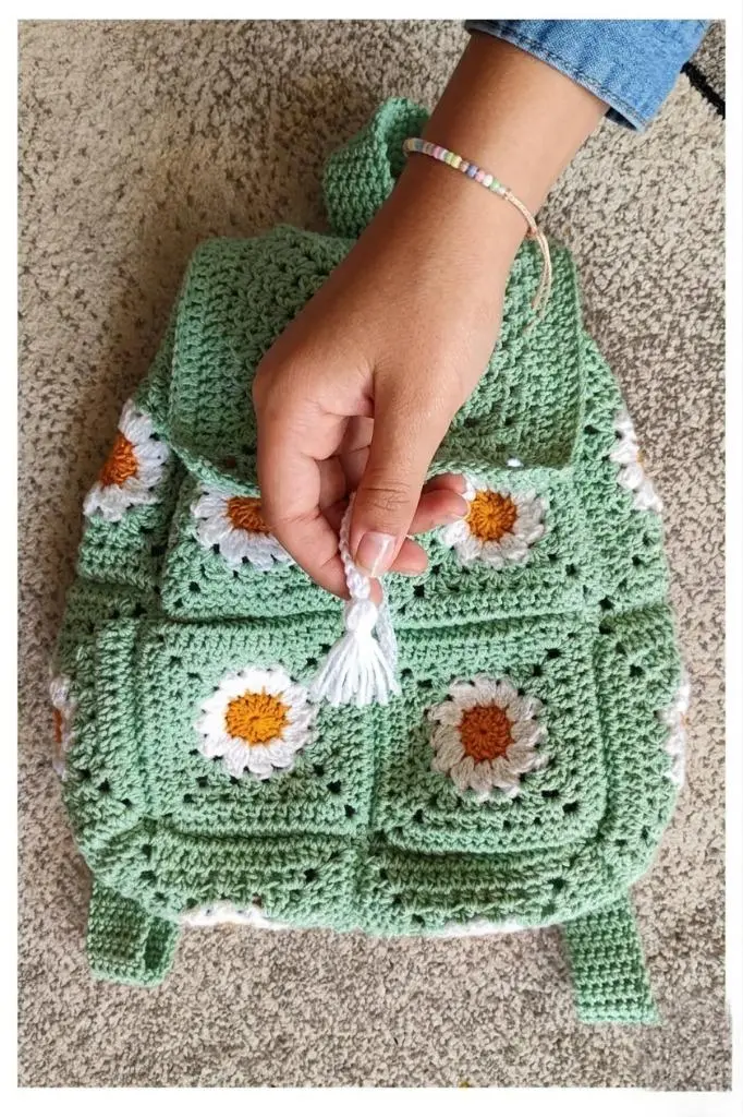 Side view of a mint green crochet backpack with daisy granny squares and adjustable straps.
