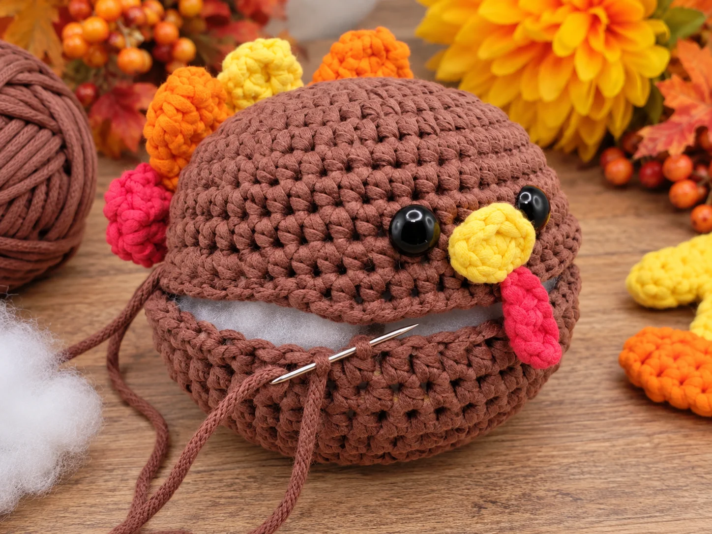 Finished Mini Turkey Squish crochet pattern with brown body, yellow feet, colorful tail feathers, beak, and red wattle