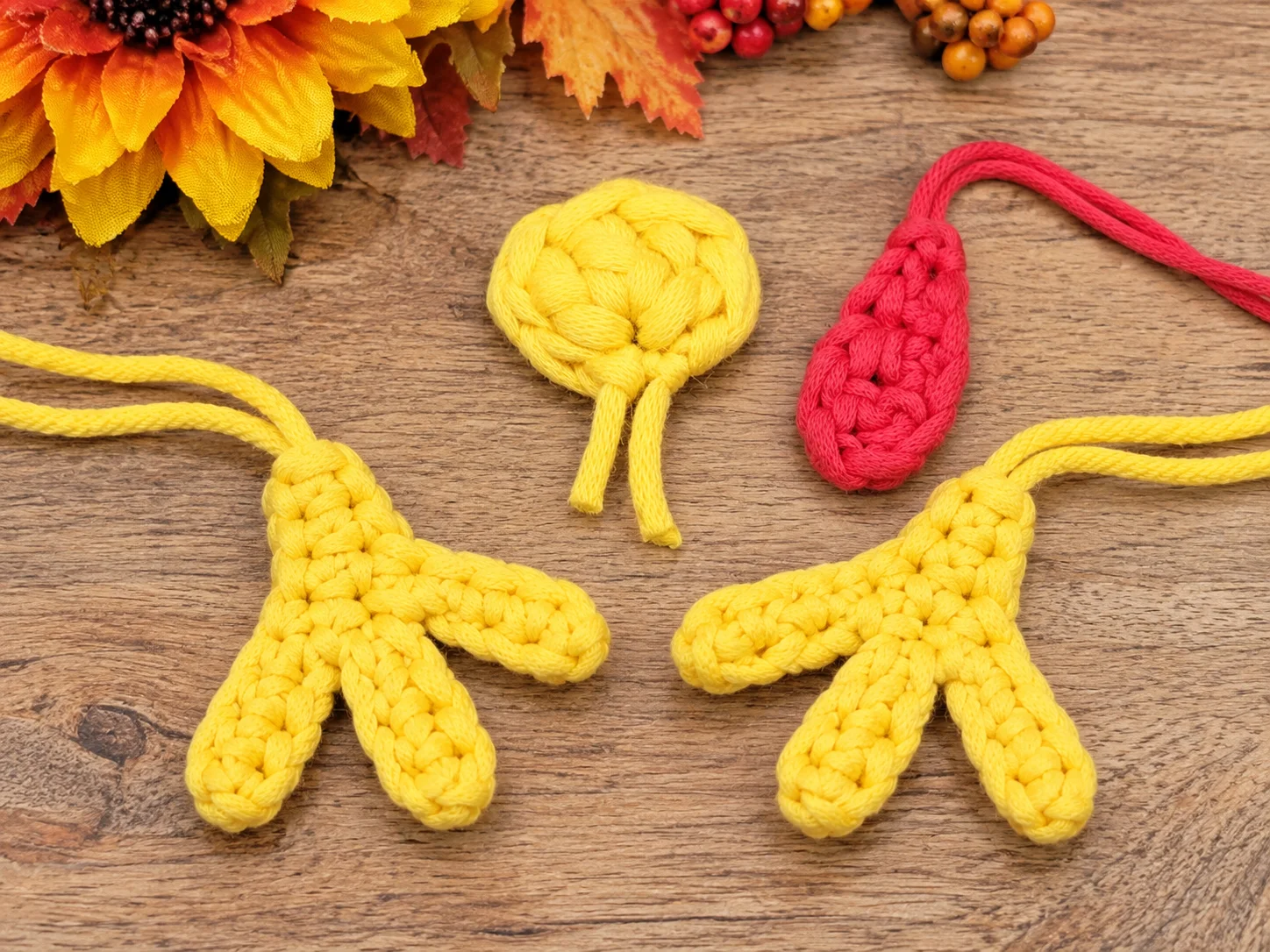 Materials for the Mini Turkey Squish crochet pattern including brown, yellow, orange and red yarn, crochet hook, safety eyes, stuffing and stitch markers