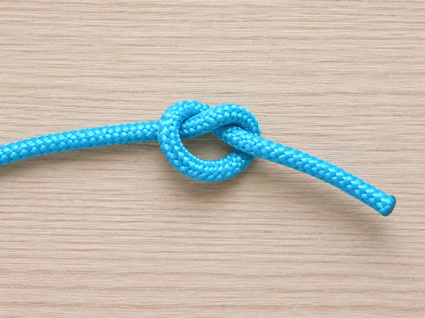 Step 3 feeding the cord end through the loop to form an overhand knot