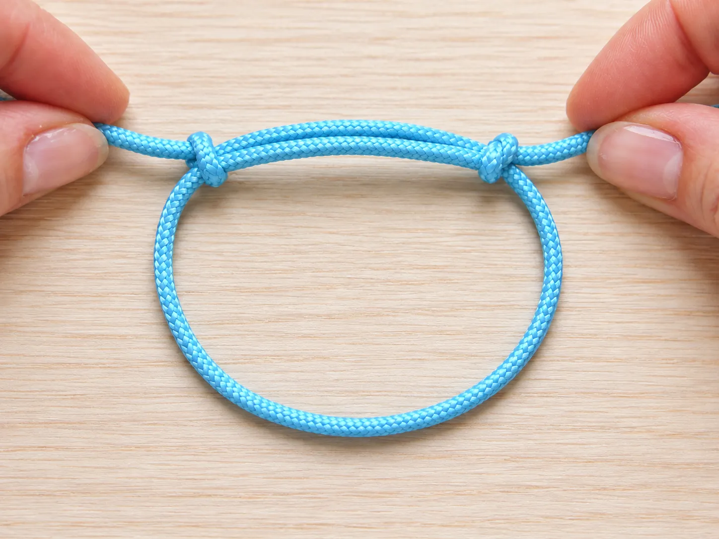 Finished adjustable sliding knot bracelet with stopper knots on the cord ends