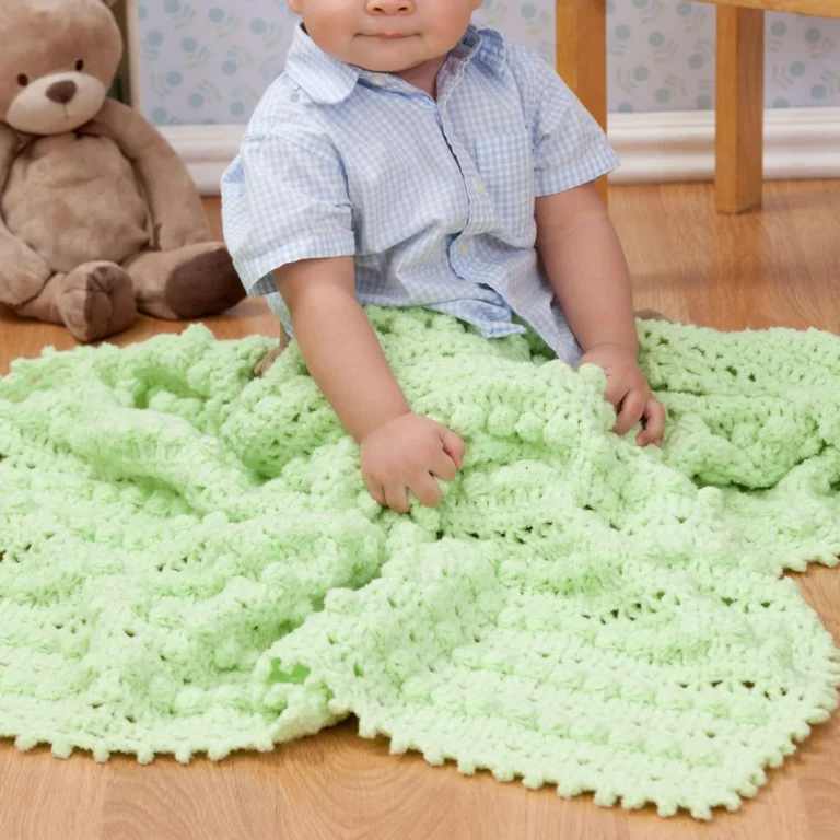 Crocheted baby blanket featuring bobble stitch design, showcasing texture and warmth.