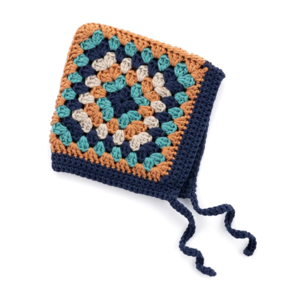 Granny Square Crochet Baby Bonnet Pattern displayed on a cute baby mannequin.